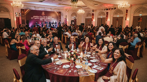 A festive indoor evening gala dinner hall filled with cheerful Ananda College alumni gathered around banquet tables celebrating a 25th batch jubilee. Soft ambient chandelier lights, maroon table accents, and laughter evoke enduring camaraderie, class, and nostalgic warmth.